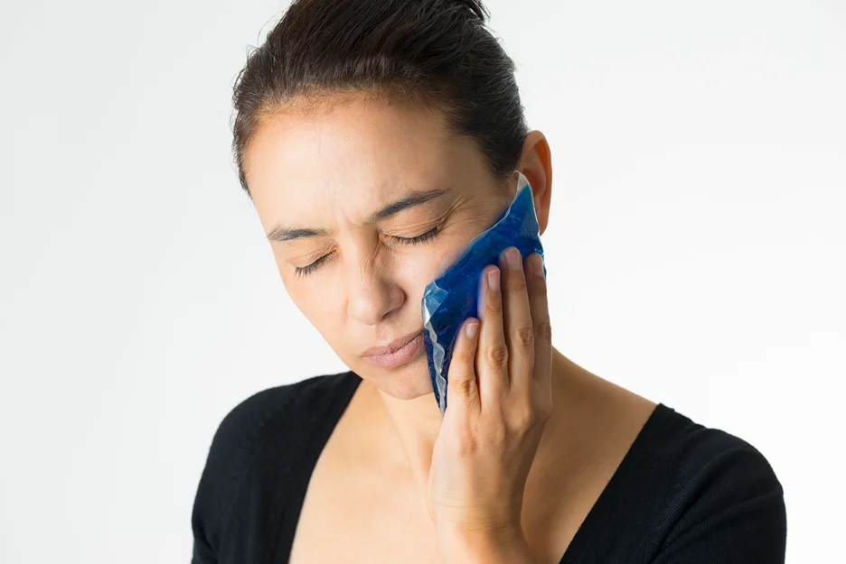 a woman put ice pack on her cheek