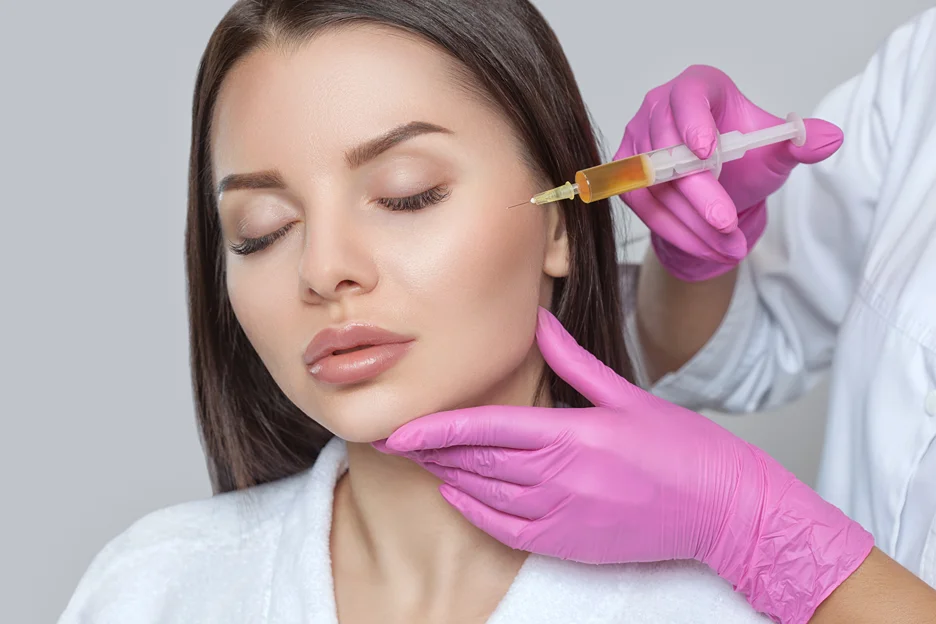 Gloved practitioner injecting cheek filler into a woman's face