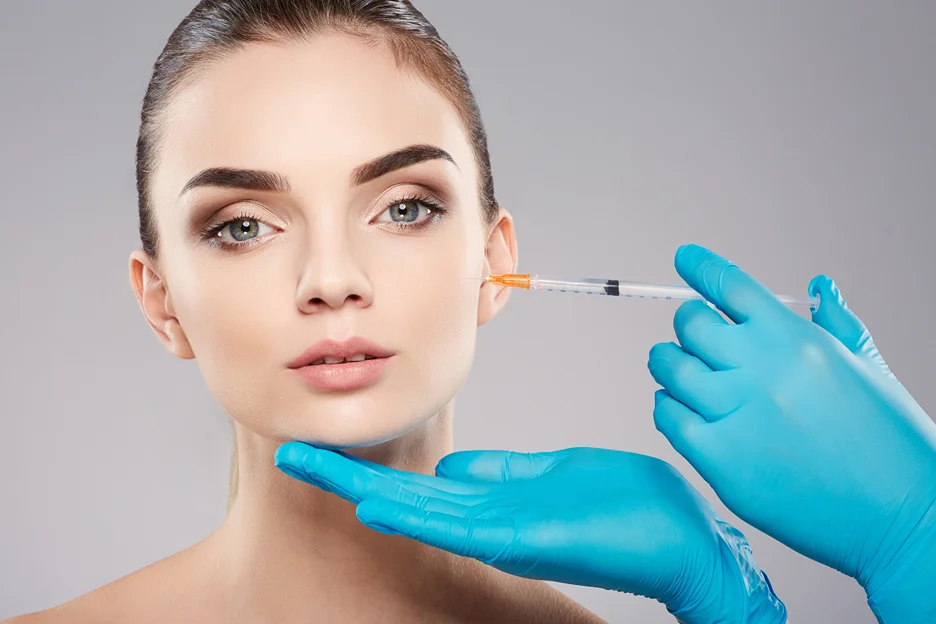 Gloved practitioner injecting cheek filler into a woman's face