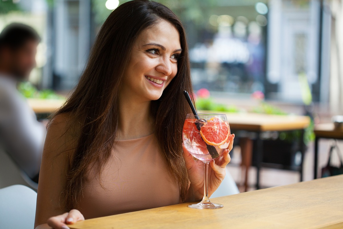 Pretty woman smiling and drinking a cocktail|Dermal FIller treatment at Dr. Lanna