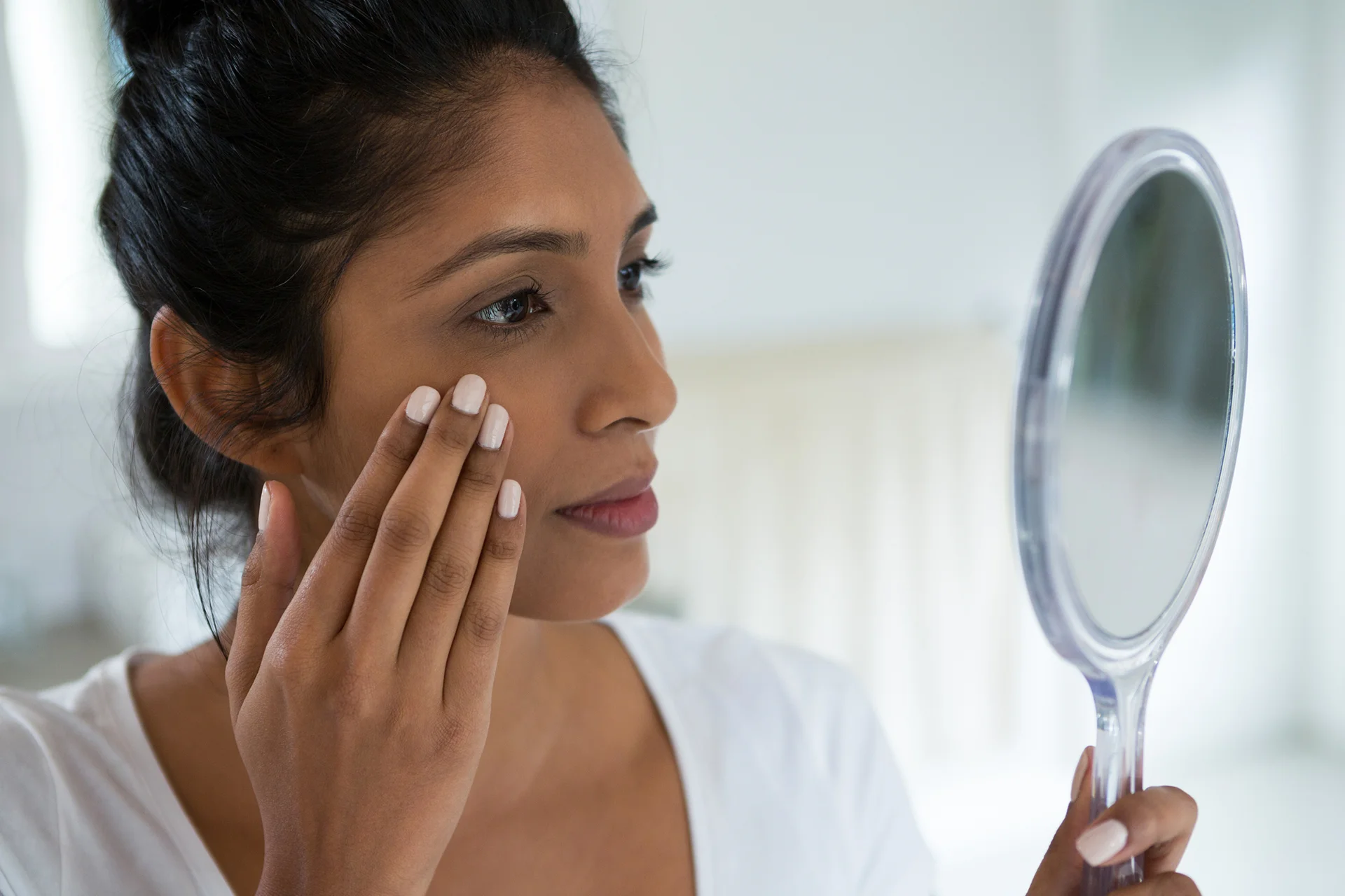 a woman touches her face in front of the mirror|a woman underwent dermal filler treatment|a woman received lip filler treatment at Dr. Lanna's clinic