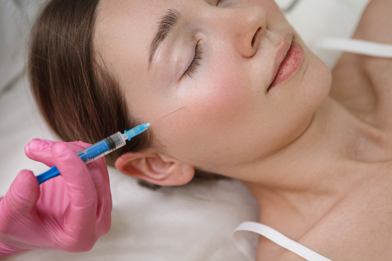Cropped close up of a woman getting cheek filler injections at beauty clinic|Side portrait view of young asian woman touching her face