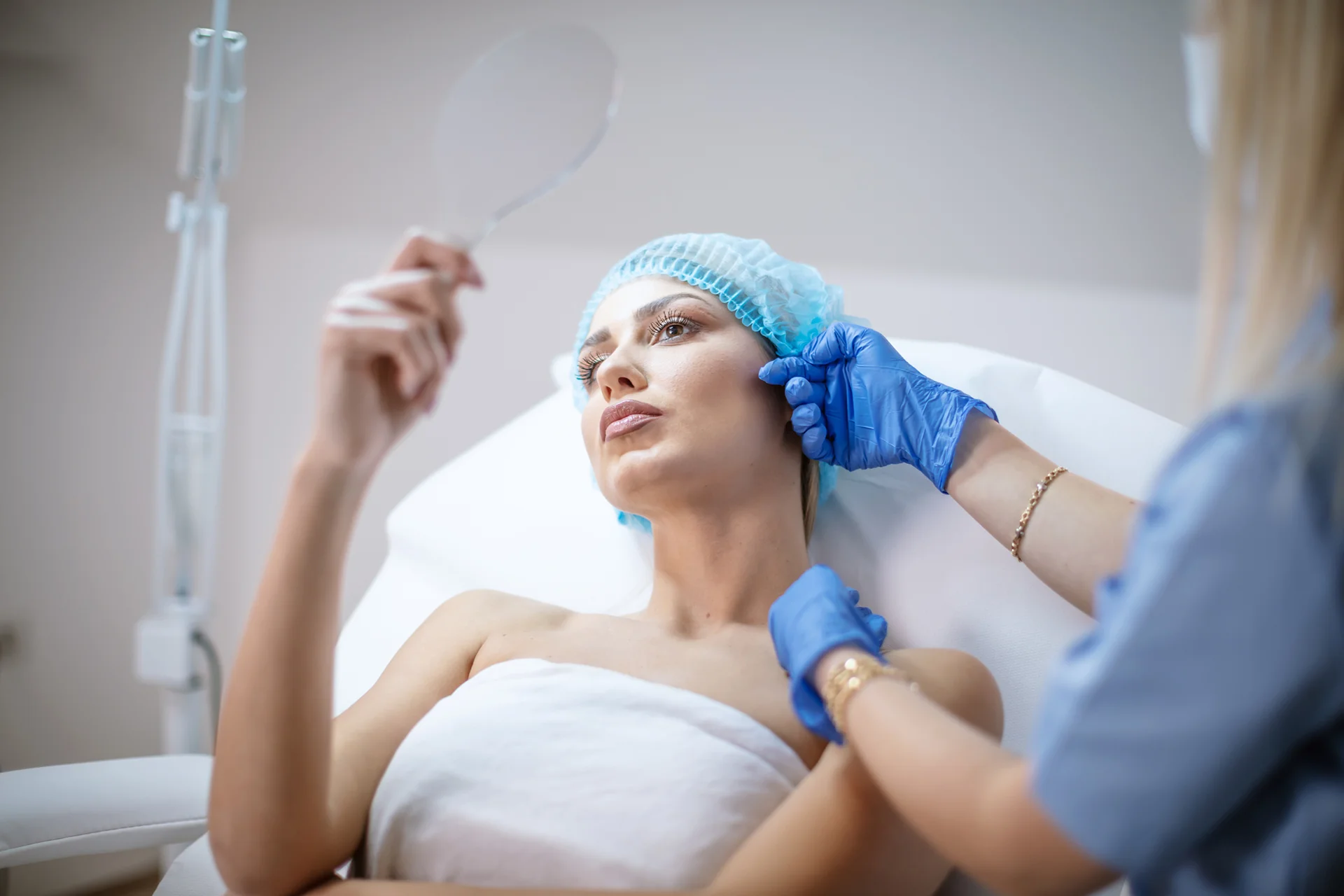 a woman checking her face in the mirror after cheek filler procedure||