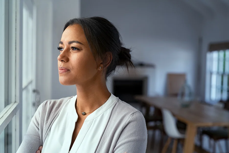a working female gazing outside through the windows