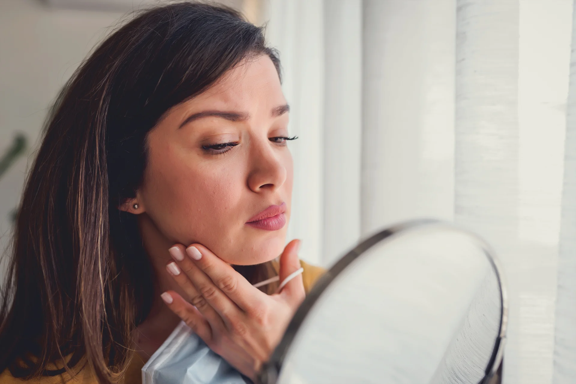a woman checking her cheeks infront of the mirror||