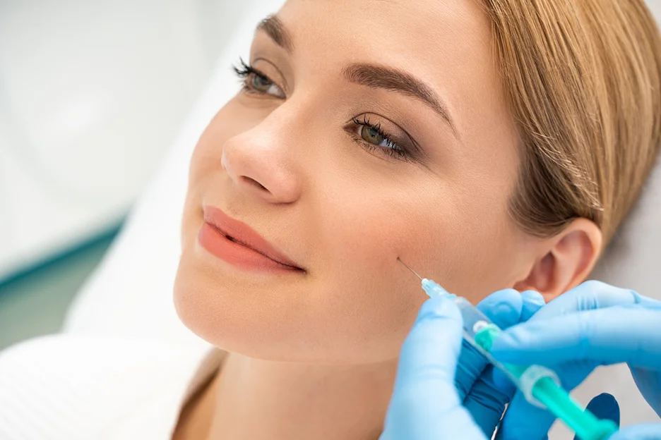Gloved practitioner injecting filler into a woman's cheek