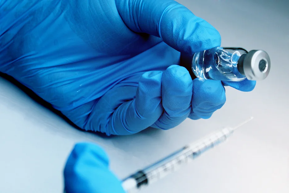 a hand holding vial and syringe