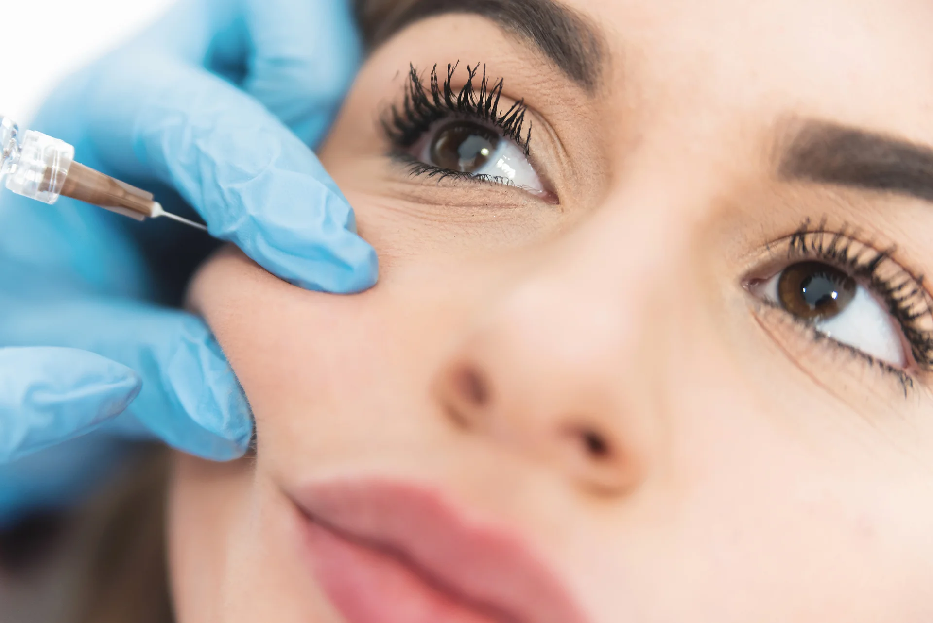 doctor holds woman's cheek to inject filler treatment|woman received cheek filler treatment in a beauty clinic